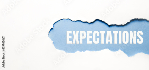 inscription Expectations word on blue torn papper photo