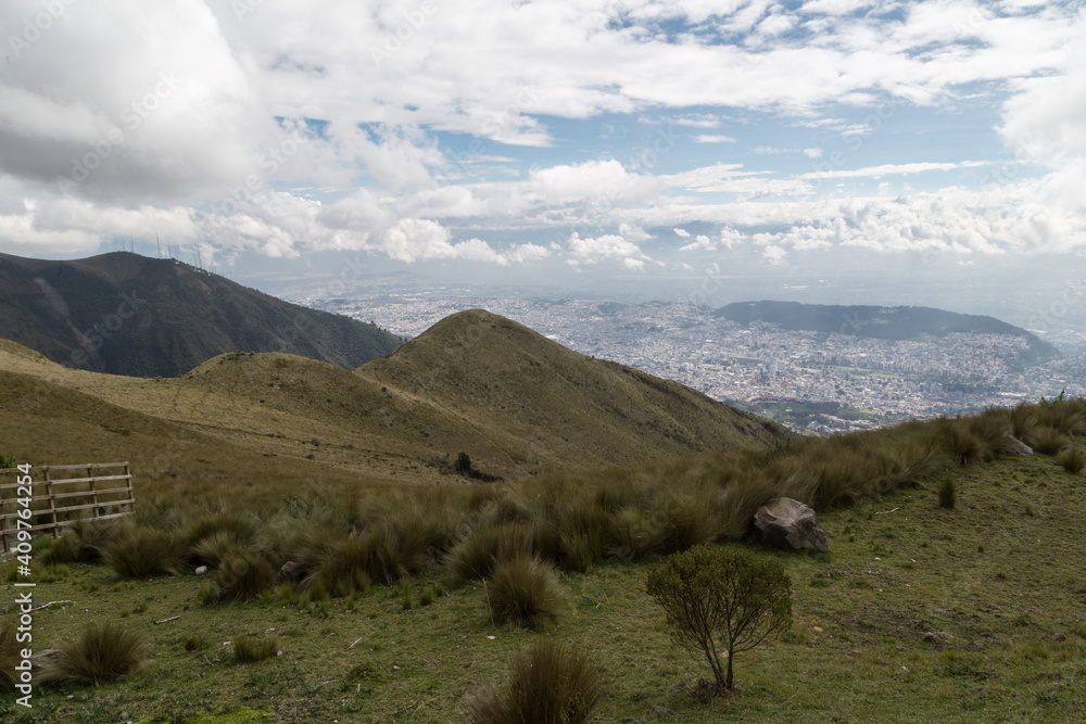 landscape of mountains with a cloudy sky with a city in the background in the middle of the andes