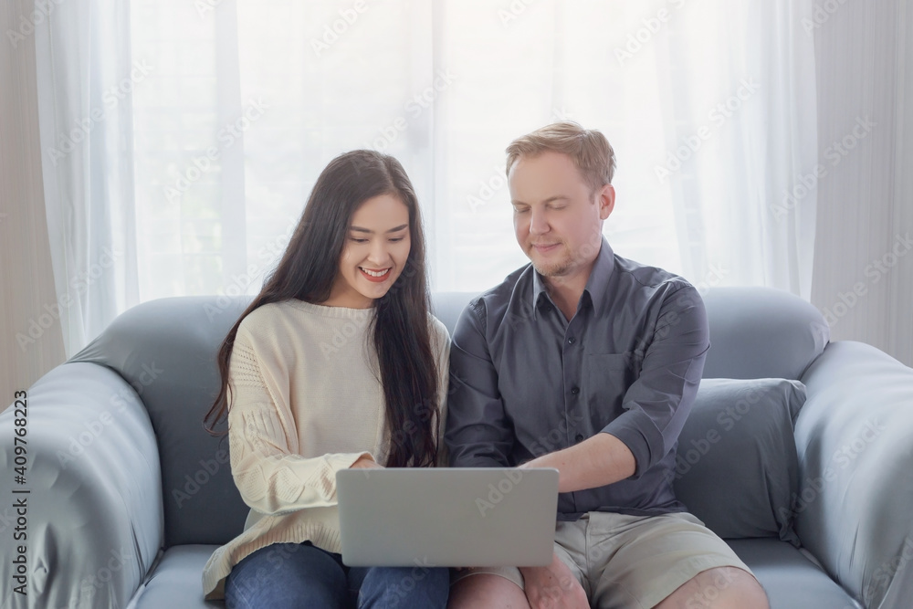 Young interracial couple using laptop making video call through the online internet at home during Covid-19 pandemic crisis Young interracial couple using laptop making video call through the online internet at home during Covid-19 pandemic crisis