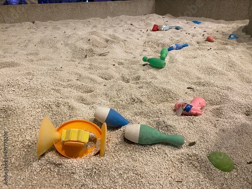 Playground with some toys like fire truck, bowling pin and bucket in the sandpit or sandbox. The place can let toddler playing with sand molds and making mudpies. Outdoor creative activities for kids. photo