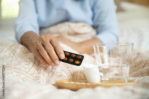 Sick Old female taking medicines, antidepressant, painkiller or antibiotic. White pill in old female hand. Old womans hands with pills on, spilling pills out of bottle.