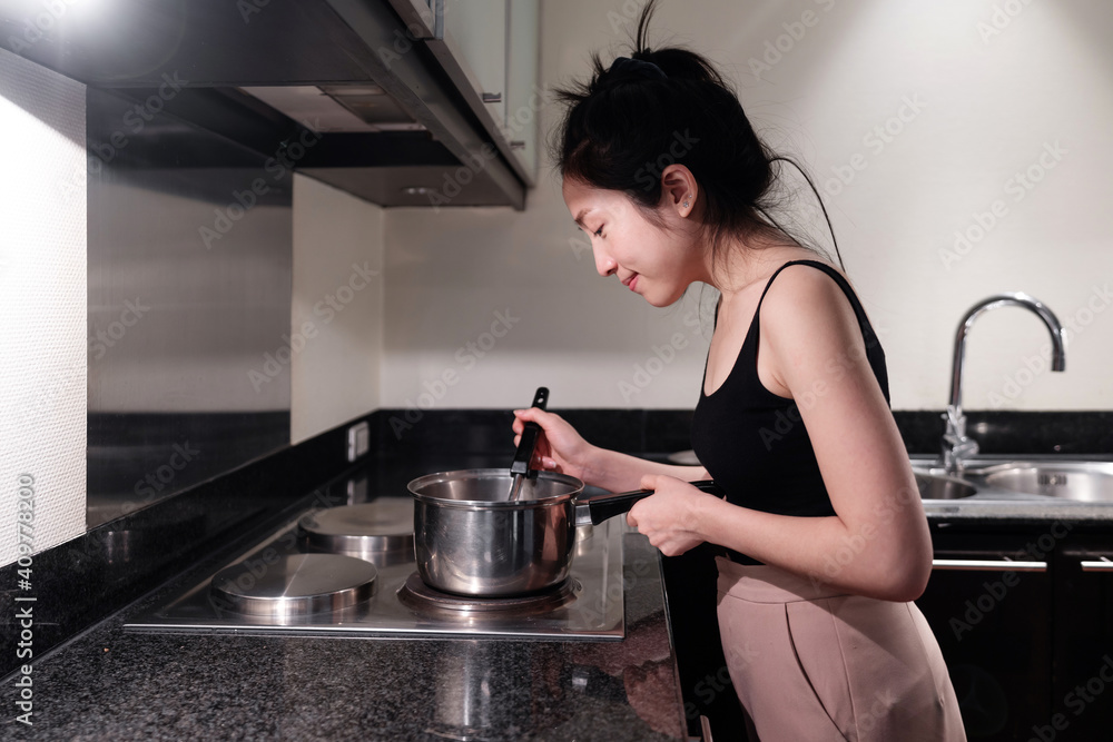 Young woman cooking in home kitchen, with smiling face Young woman cooking in home kitchen, with smiling face
