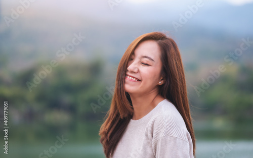 Portrait image of a beautiful young asian woman standing in front of the lake and mountains