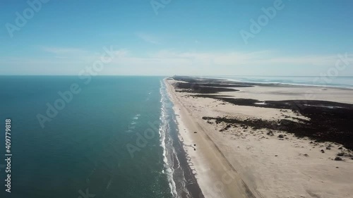 Drone high angle view of surf, beach and sand dunes at low tide on a gulf coast barrier island on a sunny afternoon, luguna on far side of island is visible - South Padre Island, Texas photo