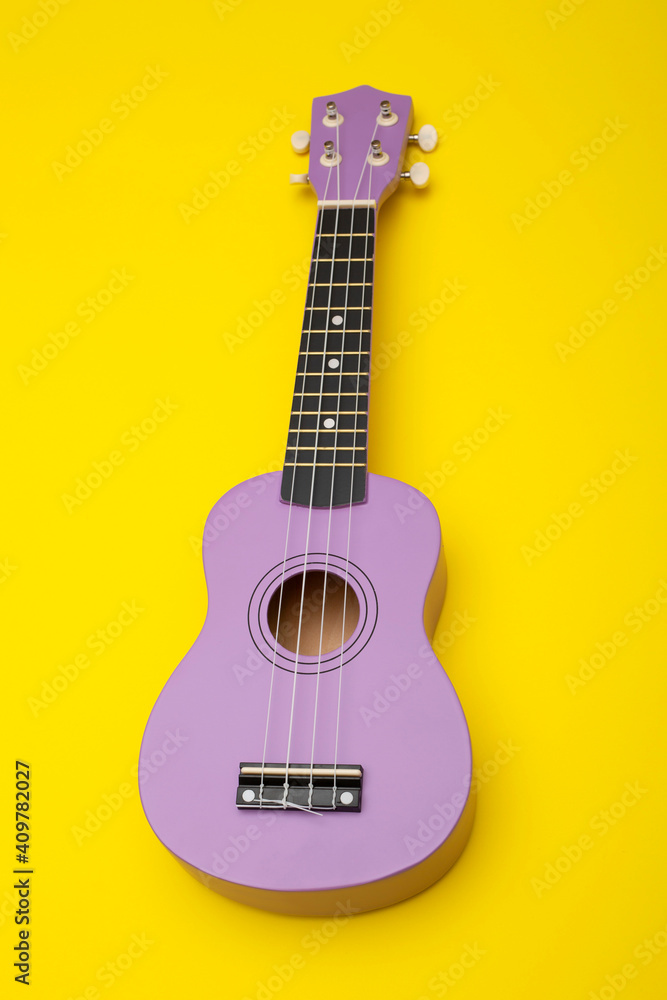 Obraz premium Four string ukulele guitar on yellow background