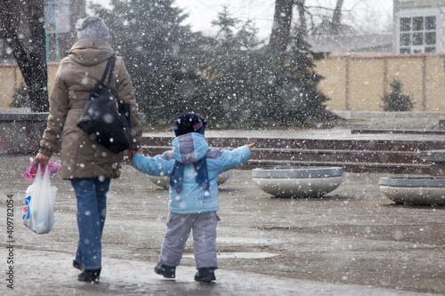 Mom and baby on the street during a snowfall