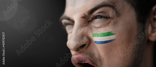 A screaming man with the image of the Sierra Leone national flag on his face photo