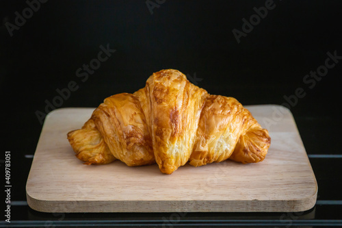 Croissant on a wooden plate on a black background
