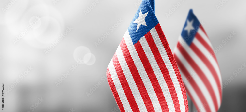 Fototapeta premium Small national flags of the Liberia on a light blurry background
