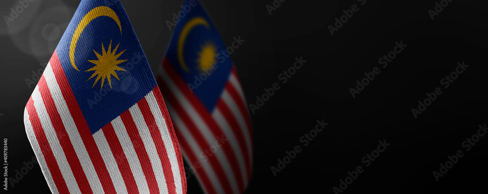Small national flags of the Malaysia on a dark background