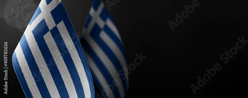Small national flags of the Greece on a dark background