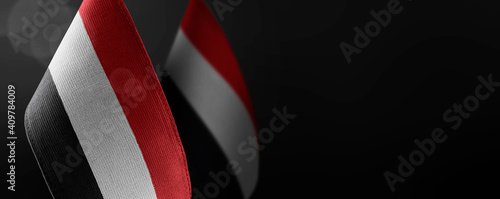 Small national flags of the Yemen on a dark background