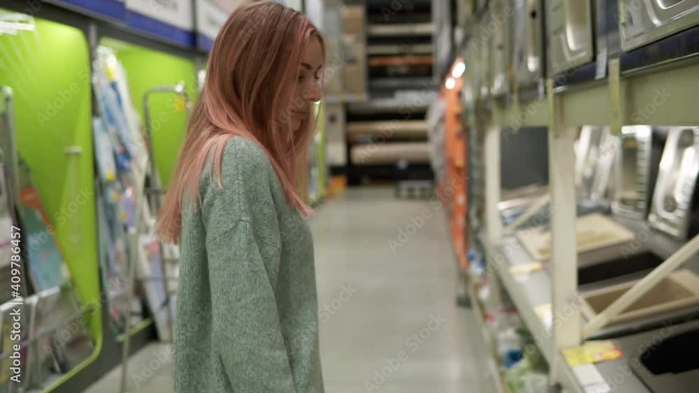Woman is choosing a new kitchen sink in a store Woman is choosing a new kitchen sink in a store