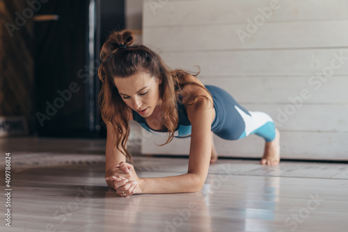 Fit woman doing plank exercise, workout at home photo