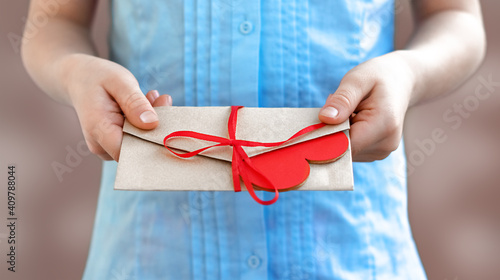 Man's hands are holding an envelope with a red heart. Female hands give a valentine. Valentine's Day, love. Declaration of love. World Day of Kindness. close-up. copy space.