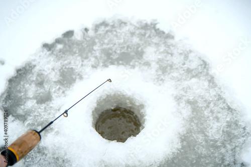 Winter fish. A hole in the ice for fishing and fishing rod.