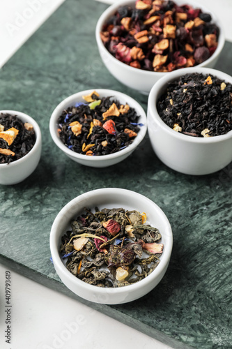 Bowls with different types of dry fruit tea on light background