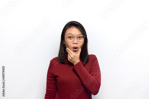 Hand on chin with surprise expression of Young beautiful asian women dress red shirt isolated on white background