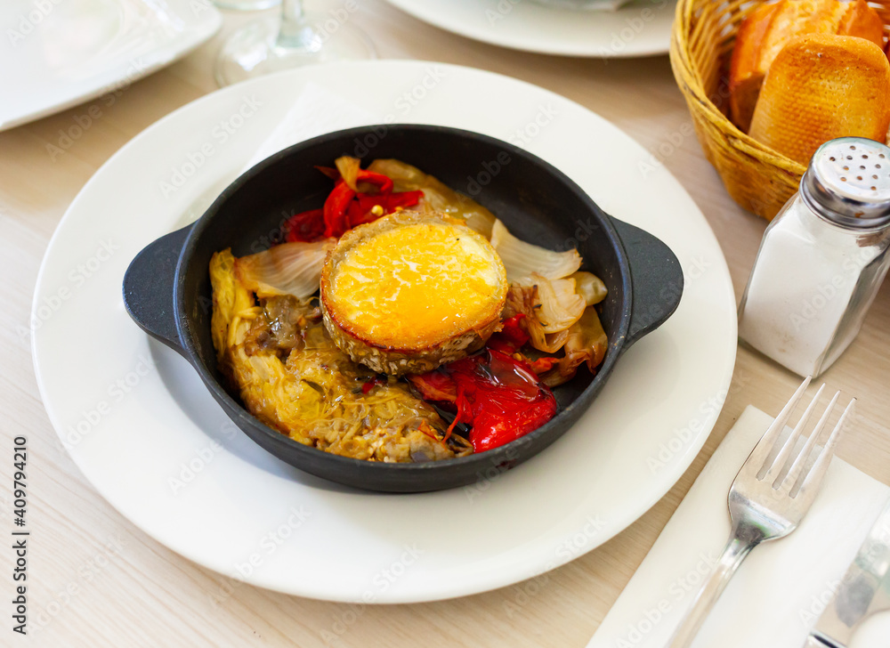 Appetizing escalibada of roasted eggplant, bell peppers, onions served with melted goat cheese. Traditional Spanish dish
