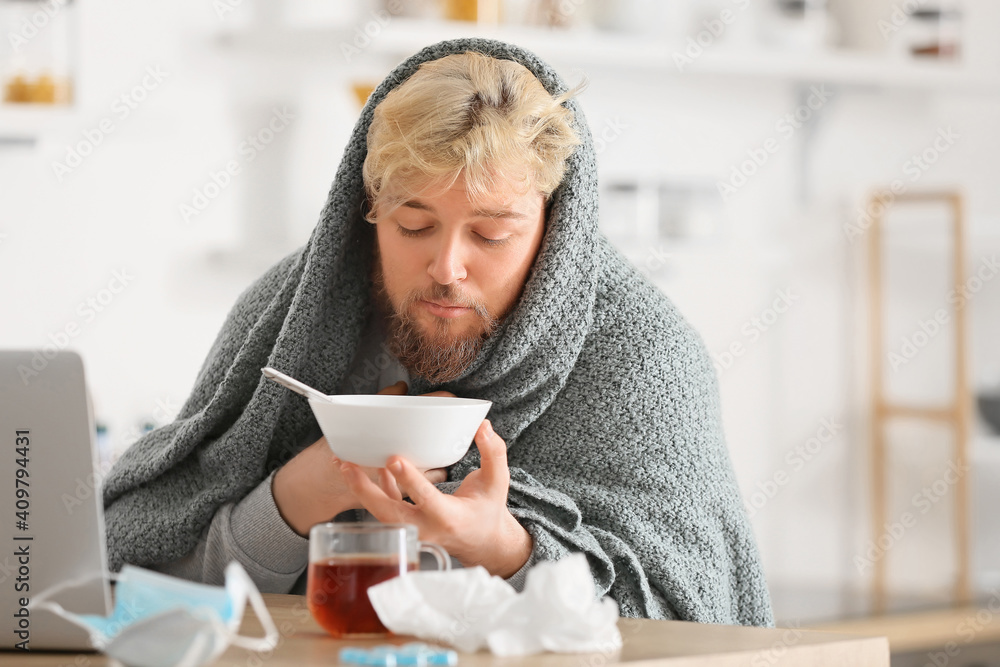 Sick young man eating chicken soup at home Sick young man eating chicken soup at home