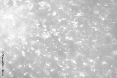 Abstract silver glitter. Festive sparkling texture. Birthday blurred light background with bokeh with copy space