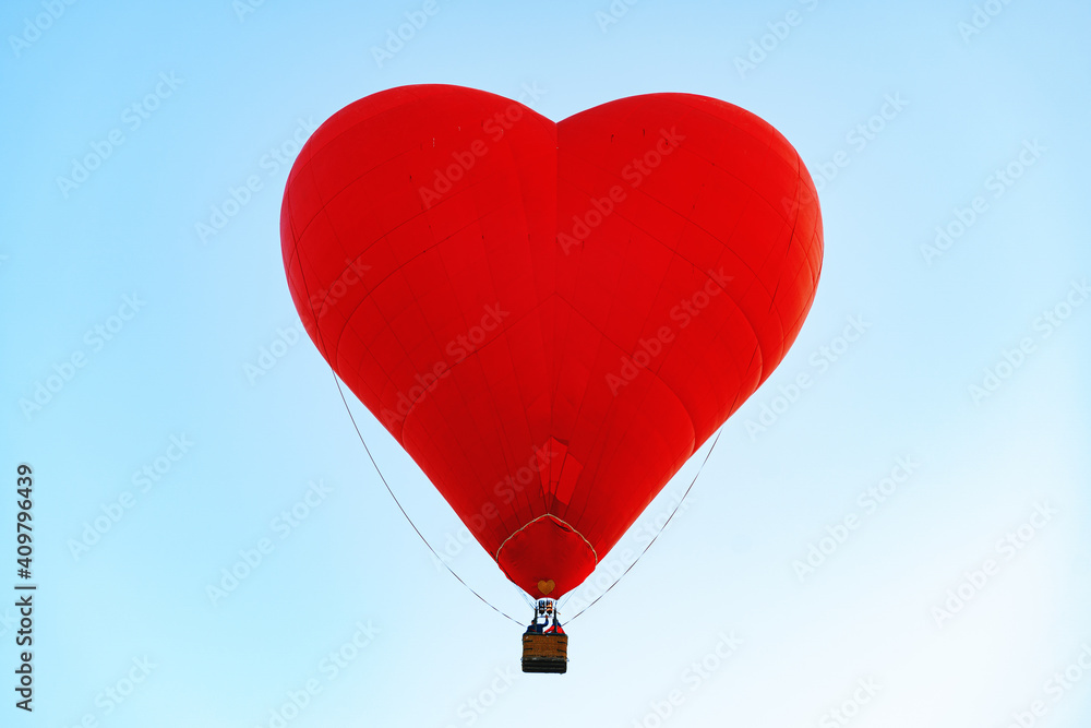 Fototapeta premium Red heart-shaped air balloon flying in the sky