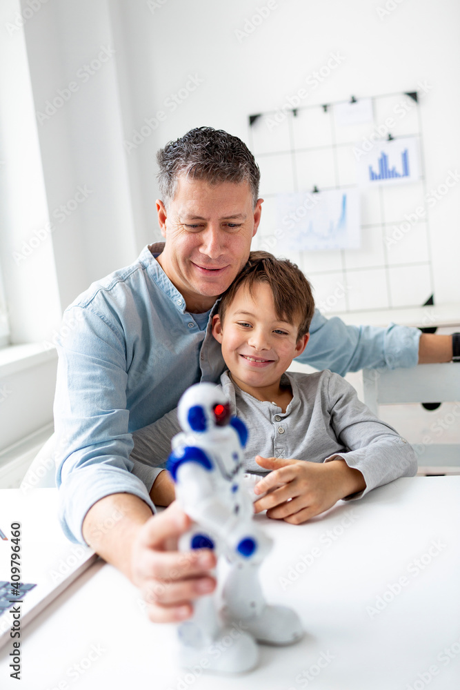 © epiximages - Family and childhood concept. Dad and son have fun together playing with a robot.