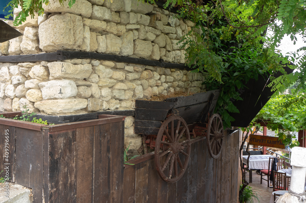 Fototapeta premium Wall of an old house with a fake wagon in which ivy grows