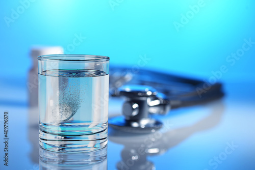 Effervescent tablet in a glass of water on blue background.