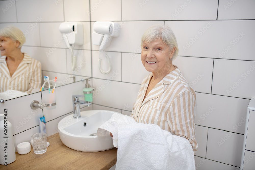 Fototapeta premium Gray-haired woman in the bathroom with a towel in hand