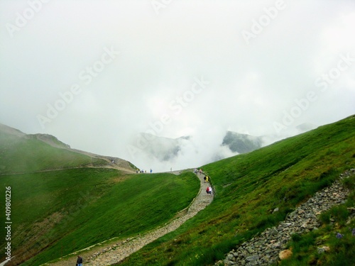 The trail in the Tatra mountains shrouded in low clouds. View from the top railway station at Kasprowy Wierch mountain. Foggy, rainy day at polish Tatra Mountains, near Zakopane ski resort. 