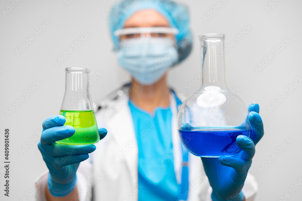 Woman scientist holding laboratory flask with chemical liquid, gray background Woman scientist holding laboratory flask with chemical liquid, gray background