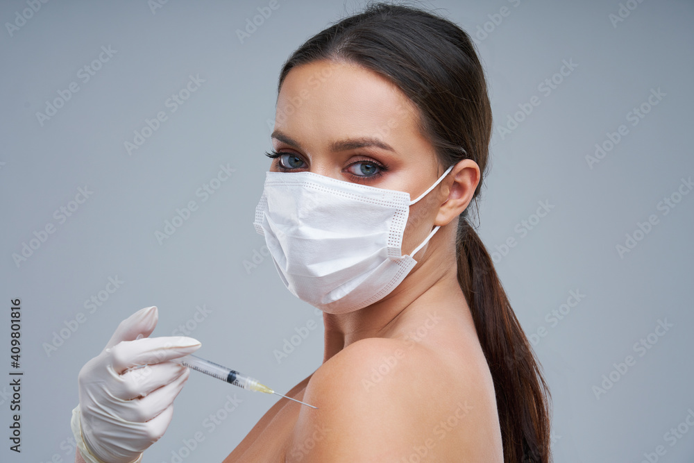 Portrait of beautiful woman holding vaccine in mask on gray background Portrait of beautiful woman holding vaccine in mask on gray background