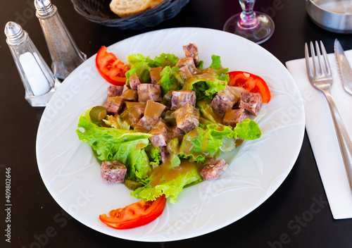 Traditional French cuisine, salad with chopped headcheese, fresh lettuce leaves, pickled cucumbers and tomatoes