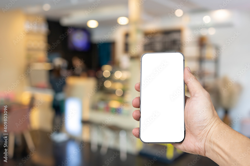 Mockup image of hand holding new modern smartphone with blank white screen in the coffee shop. Mockup image of hand holding new modern smartphone with blank white screen in the coffee shop.