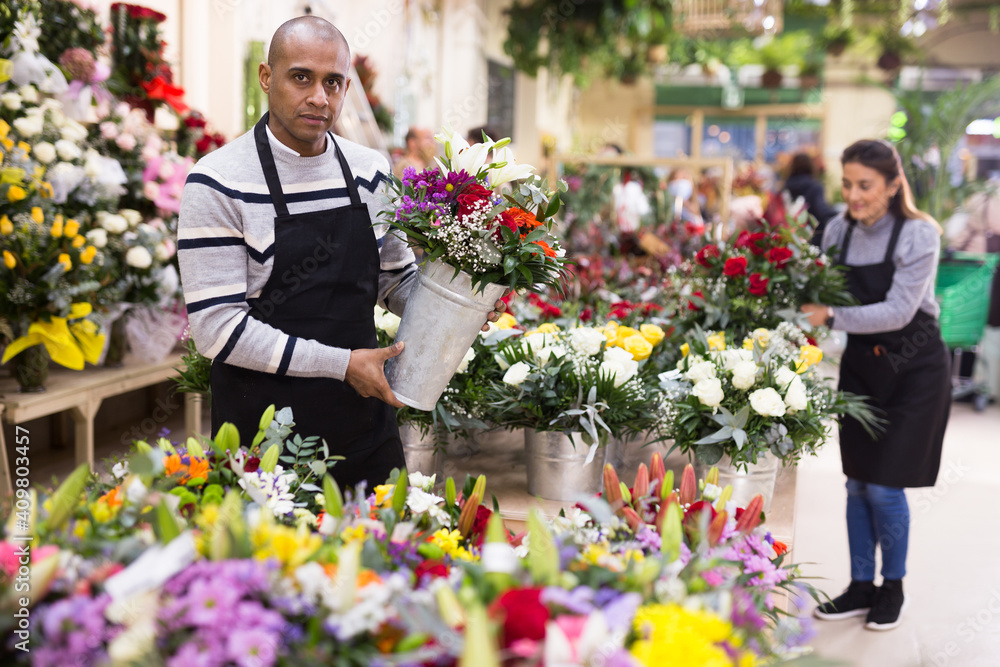 Fototapeta premium Male flower seller prepares a luxury bouquet at a flower shop