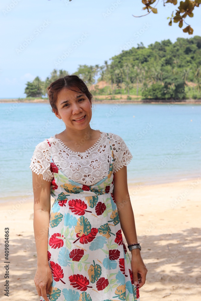 Asian one woman, Thai ethnicity, cute, tie black hair, wear a colorful pattern. Island vacation travel in Thailand Standing on the beach in the sand Behind the sun shines through the sea and trees. Asian one woman, Thai ethnicity, cute, tie black hair, wear a colorful pattern. Island vacation travel in Thailand Standing on the beach in the sand Behind the sun shines through the sea and trees.