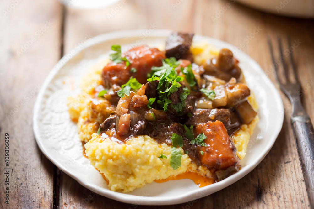 Boeuf bourguignon with carrots, mushrooms, topped with parsley served with polenta Boeuf bourguignon with carrots, mushrooms, topped with parsley served with polenta