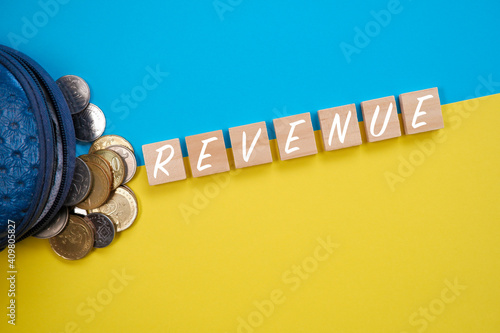 Concept image of Revenue with coins as props over striking blue and yellow background