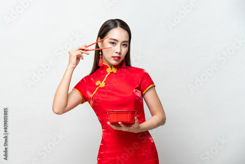 Fotografie Beautiful Asian woman in traditional red Chinese qipao dress holding food box an