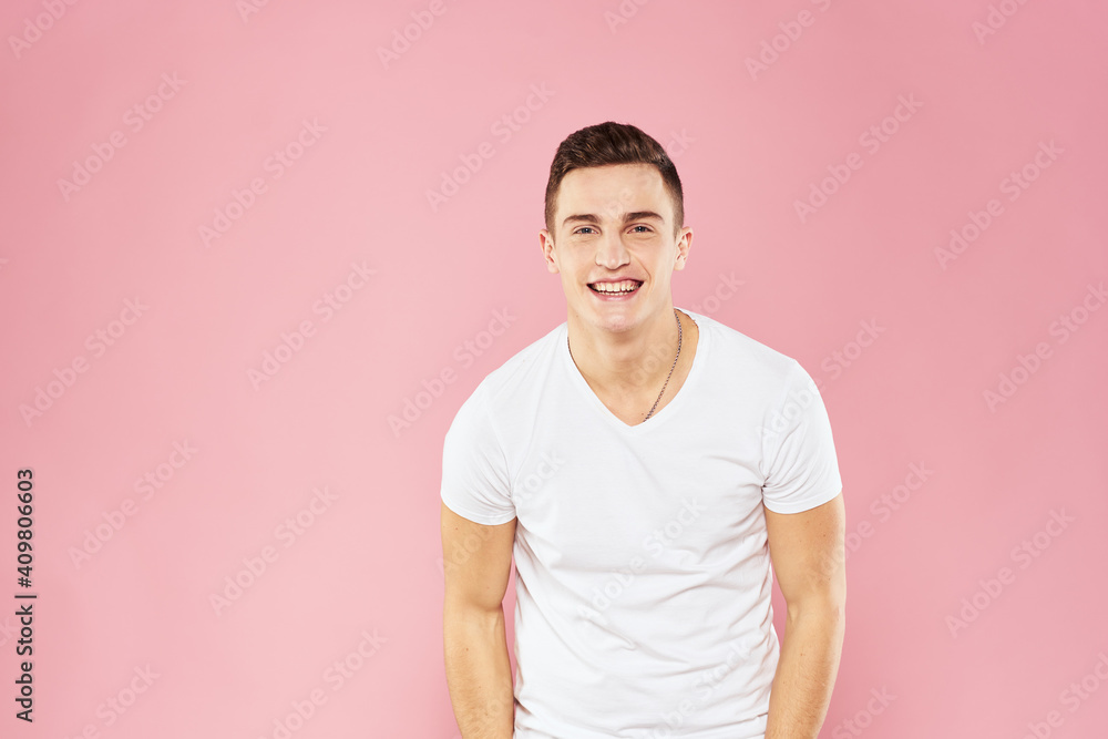 Obraz premium Cheerful handsome man in white t-shirt emotions pink isolated background