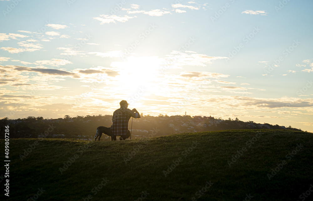 Man whit a Dog Against the Sun Watching the Sunset in a Hill.