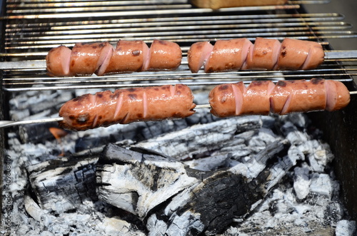 Sausages are cooked on a grill on coals . BBQ, outdoor barbecue . photo