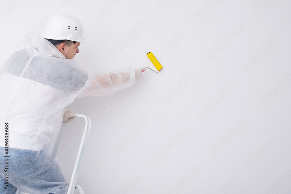 the worker glues the wallpaper with a roller, expelling air and glue the worker glues the wallpaper with a roller, expelling air and glue