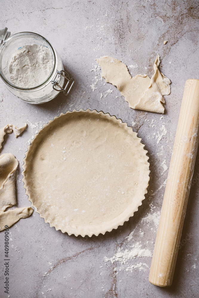 Overhead shot showing process of preparing a pie or fruit tart over a natural stone background. The photo includes flour, pieces of dough and a rolling pin. Overhead shot showing process of preparing a pie or fruit tart over a natural stone background. The photo includes flour, pieces of dough and a rolling pin.