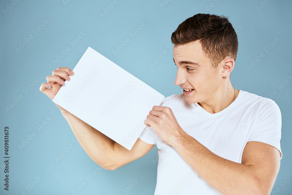 man holding a sheet of paper in his hands white t-shirt cropped view blue background man holding a sheet of paper in his hands white t-shirt cropped view blue background