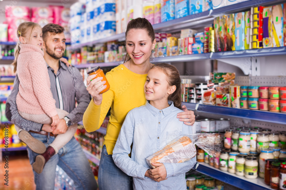 Happy parents with two daughters choosing a fresh products at the food store