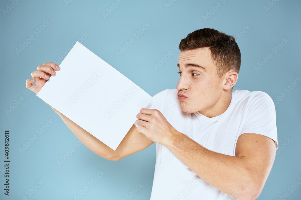 man holding a sheet of paper in his hands white t-shirt cropped view blue background man holding a sheet of paper in his hands white t-shirt cropped view blue background