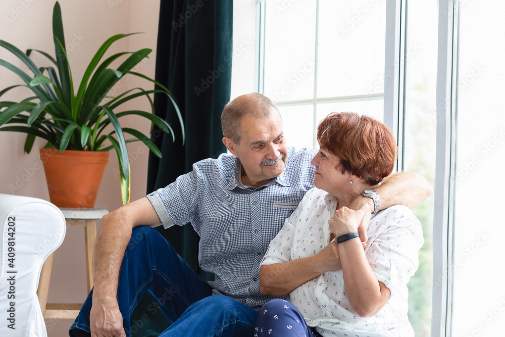 Fototapeta premium Man and woman sitting by the window hugging and smiling. Life style
