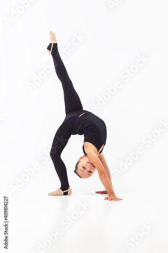Girl gymnast doing exercises in black sportswear on a white background. Acrobatics. Vertical format